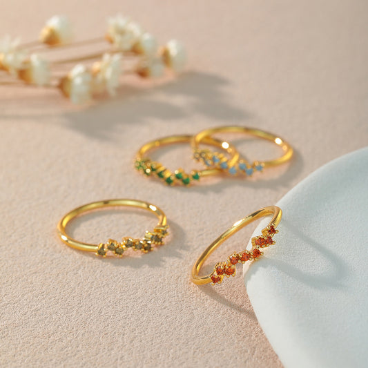 Gold rings with gemstones on a beige surface