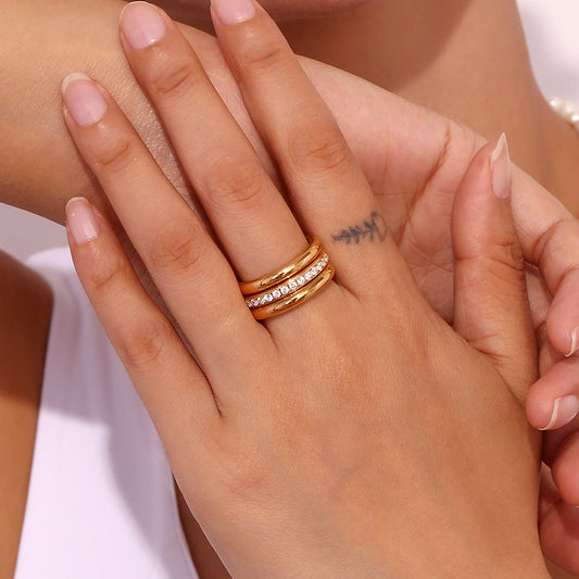 Close-up of a hand wearing a gold ring set, held by another person.