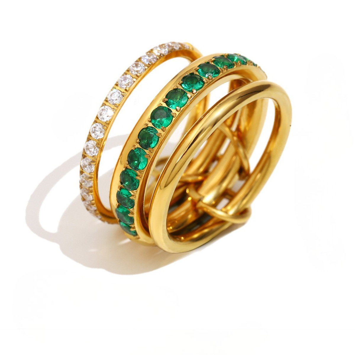 A gold-plated triple-band ring featuring one band set with round clear cubic zirconia stones and another with round green emerald-cut stones, shown on a white background with a soft shadow.