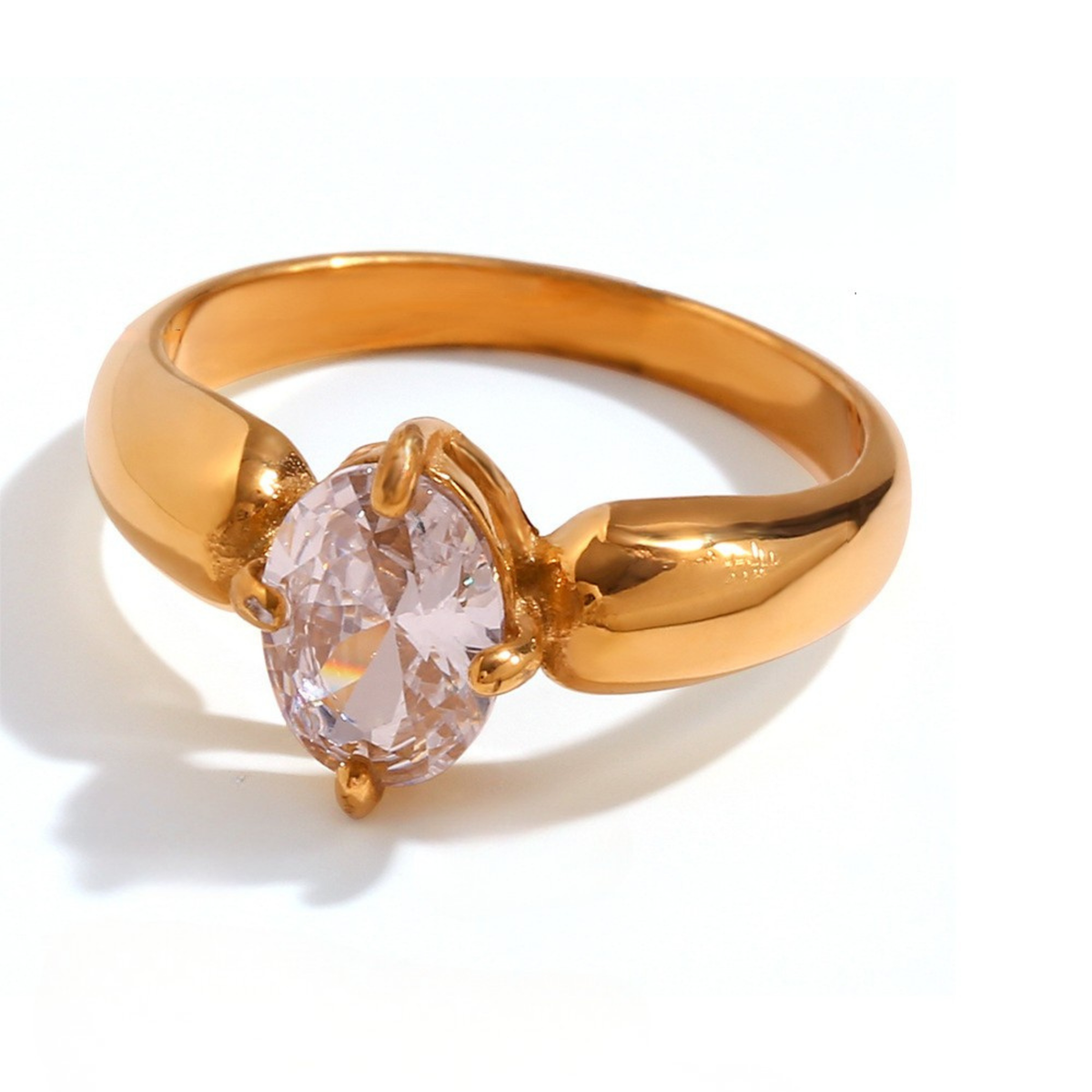 A gold ring featuring an oval-cut clear gemstone in a prong setting, shown on a clean white background with a soft shadow.