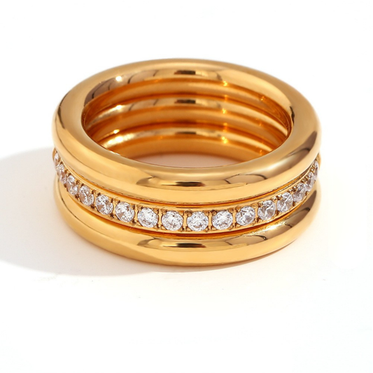 A gold-plated multi-band ring featuring a central channel set with clear round-cut stones, photographed on a clean white background.