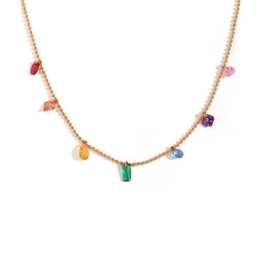 A gold beaded necklace featuring a series of small, colorful gemstone charms in red, orange, yellow, green, blue, and purple, displayed on a clean white background.
