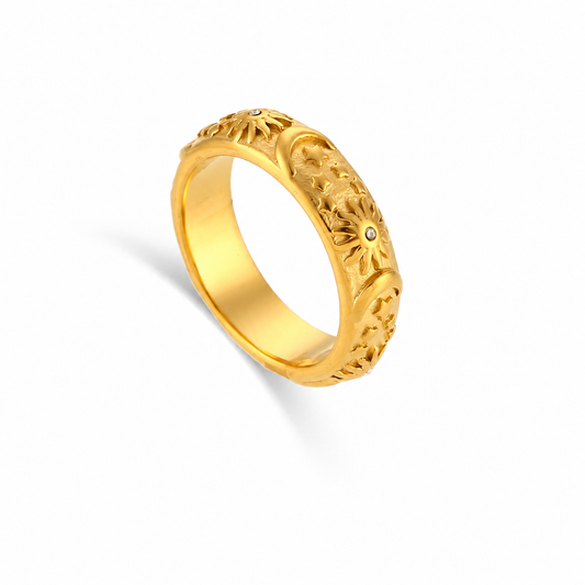 A gold ring with intricate sun, moon  and stars filigree cutouts and small round inset stones, shown on a clean white background.
