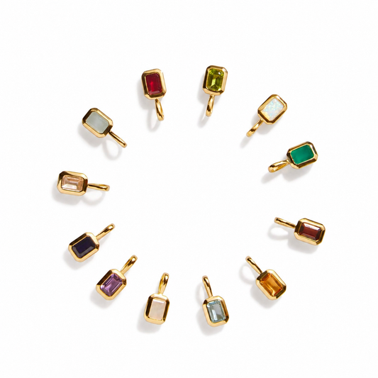 Twelve small gold Birthstone charms with different colored stones, arranged in a circular pattern on a white background.