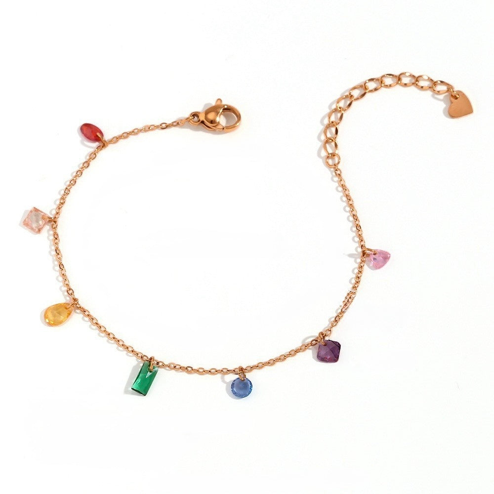 A delicate gold chain bracelet featuring multiple small, colorful gemstone charms in various shapes, displayed on a clean white background.