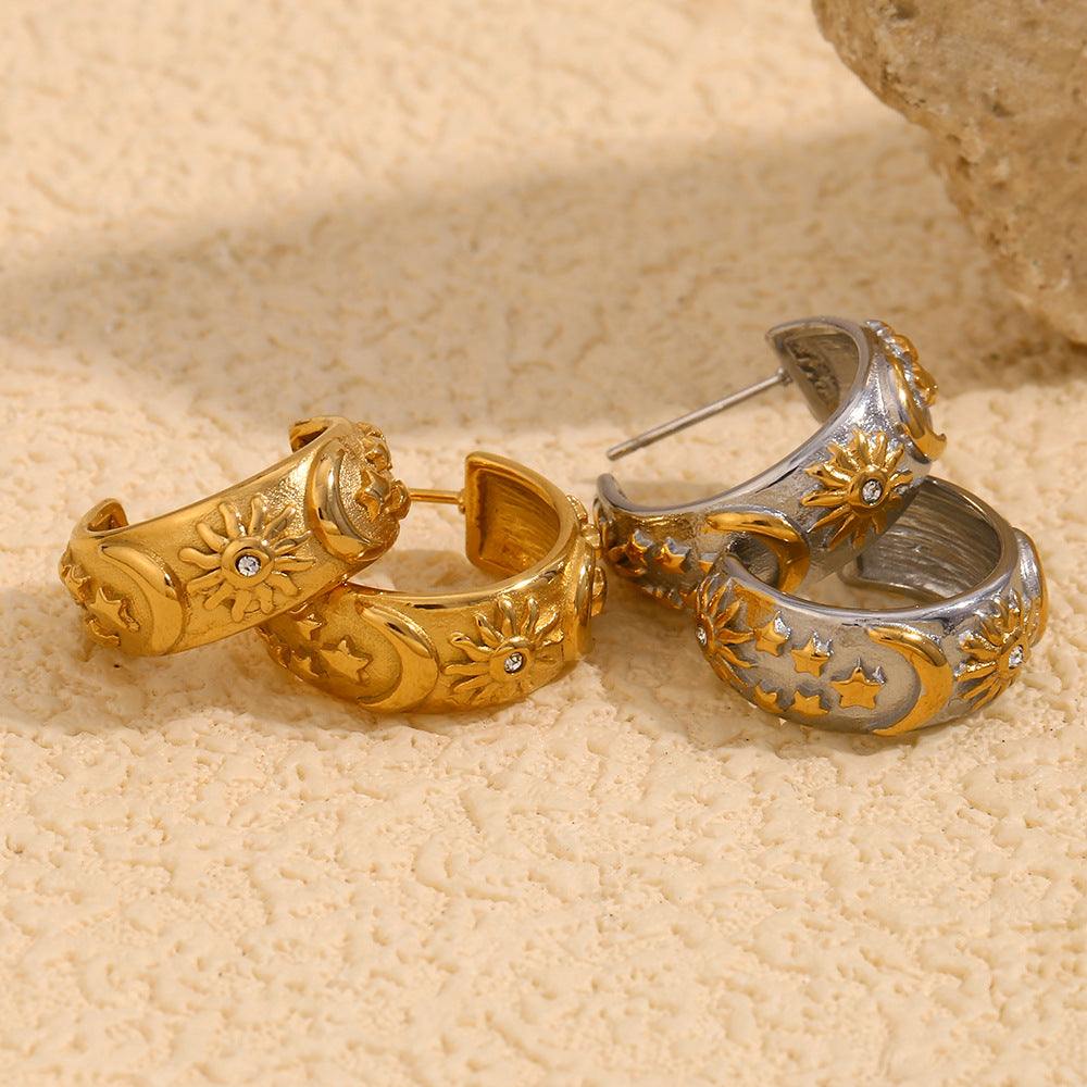 Pair of gold and silver hoop earrings on a beige surface