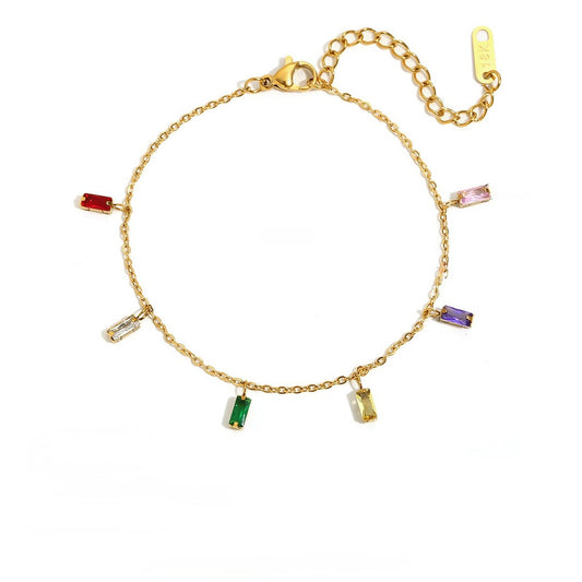 A gold chain bracelet with seven small rectangular baguette gemstones in various colors (red, pink, purple, green, yellow, clear, and silver-toned) arranged in a circle on a white background.