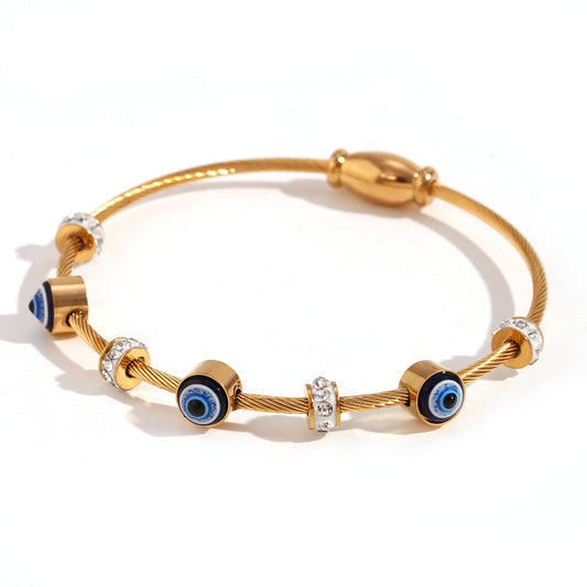 Gold bracelet with blue evil eye beads on a white background