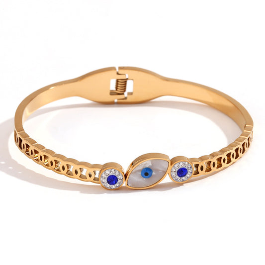 Gold bracelet with eye design and crystals on a white background