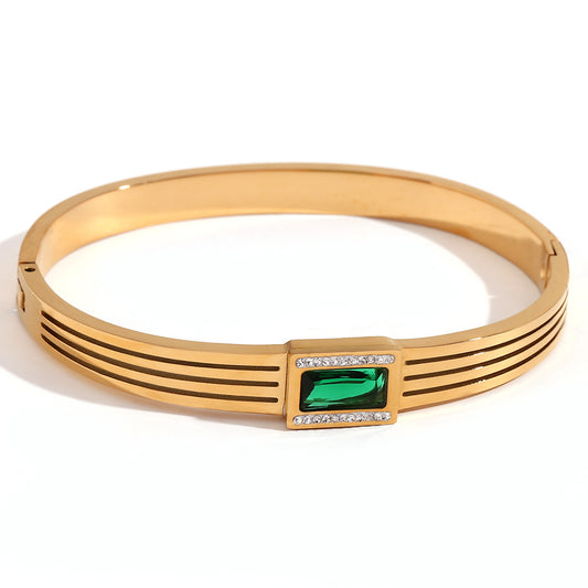 Gold bracelet with a green gemstone and diamonds on a white background