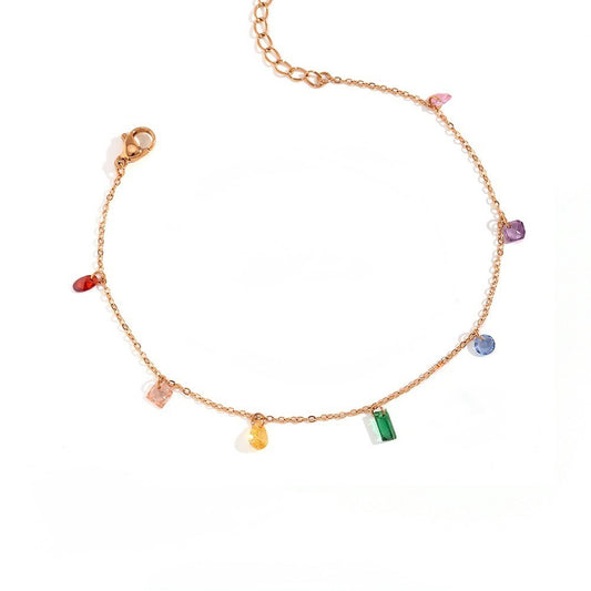 A delicate gold chain bracelet featuring multiple small, colorful gemstone charms in various shapes, displayed on a clean white background.