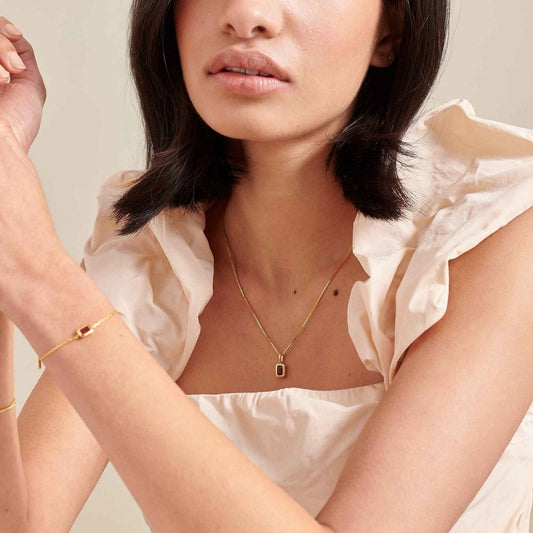 Woman wearing a Birth stone charm necklace on a neutral background