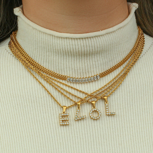 Gold necklaces with letter pendants on a white turtleneck