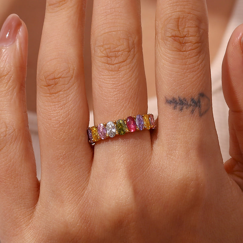 Multicolored gemstone ring on a finger with a blurred background