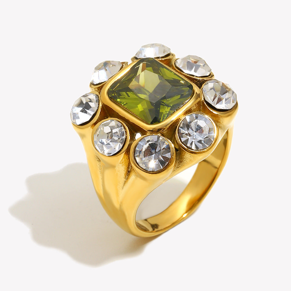 Gold ring with a green gemstone and clear stones on a white background
