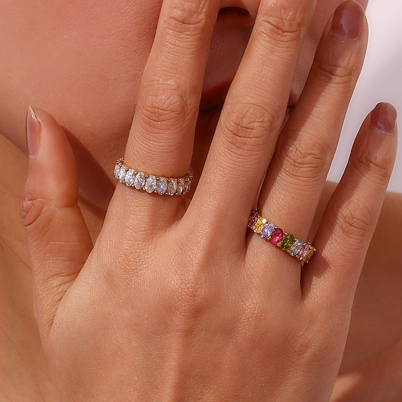 Hand wearing two rings with gemstones on a neutral background