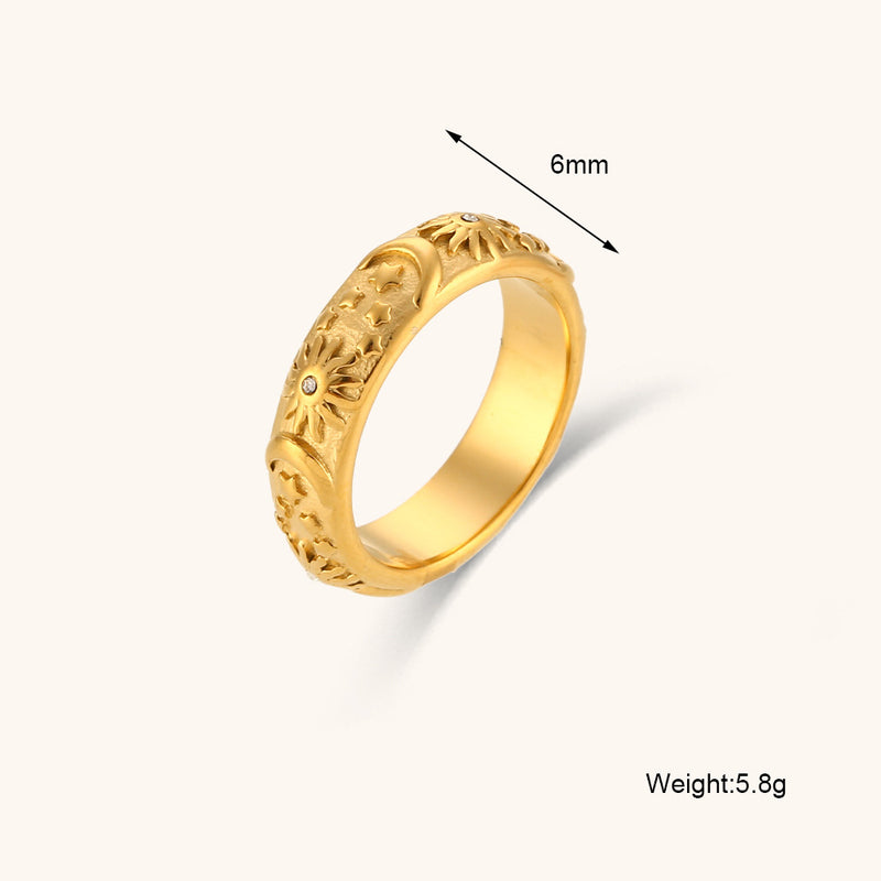 A gold ring with Sun, moon and stars engravings and a small stones, shown on a light beige background with a 6mm size indicator and weight text.