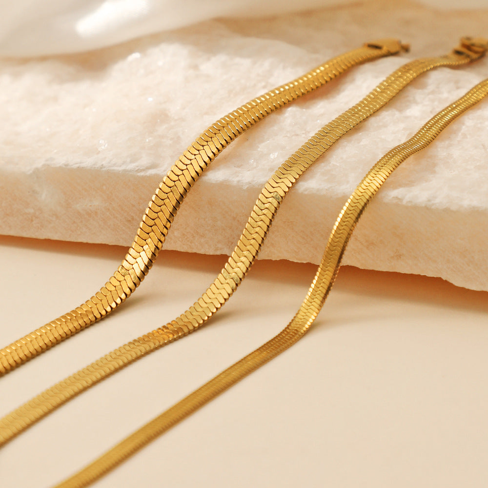 Gold snake chains on a textured beige surface