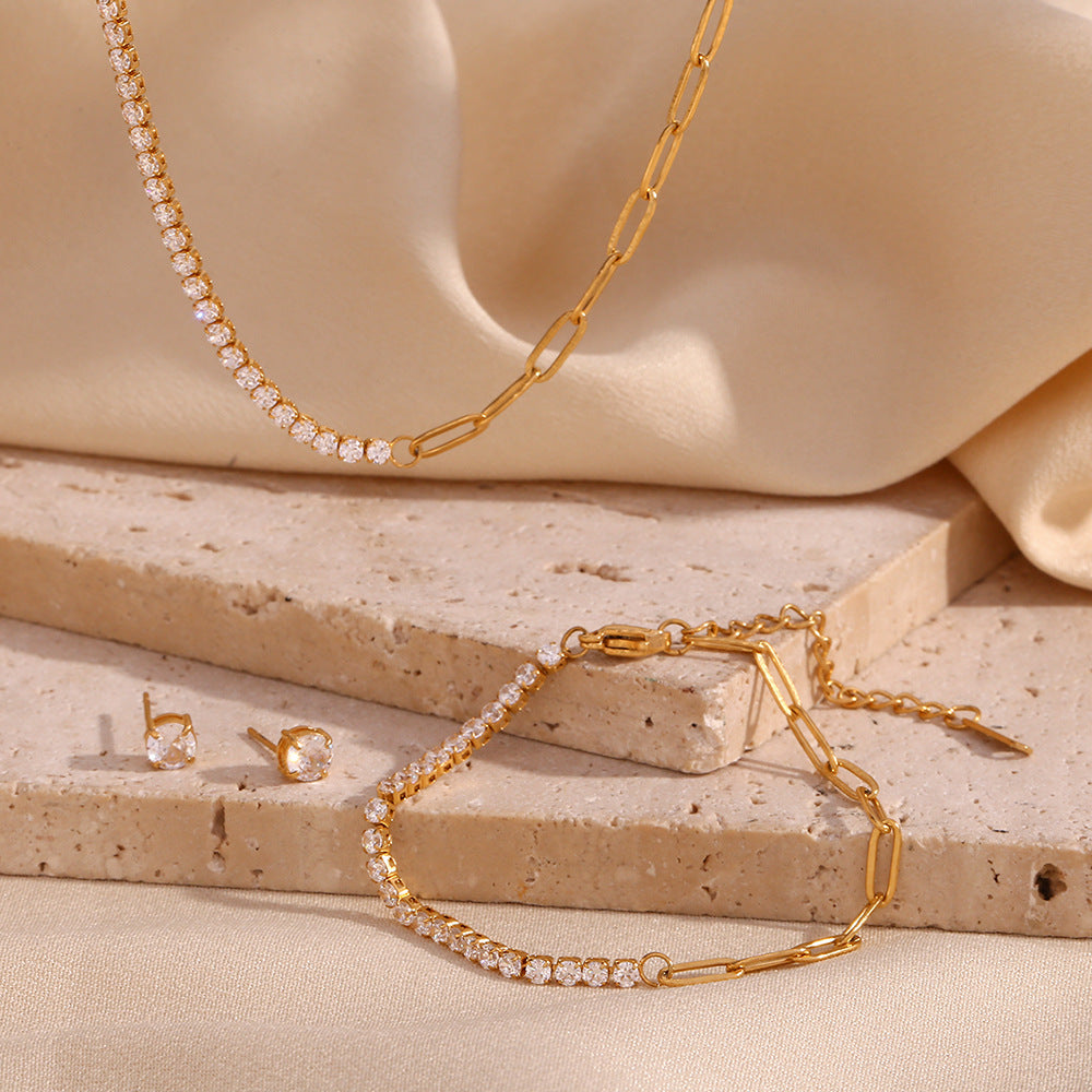 Gold jewelry set including necklace, bracelet, and earrings on a beige stone surface.